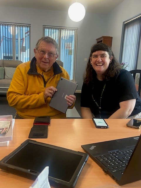 Two people sat at a table with laptop and phones