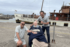 Three people on a dock beside the vintage ship Waverley